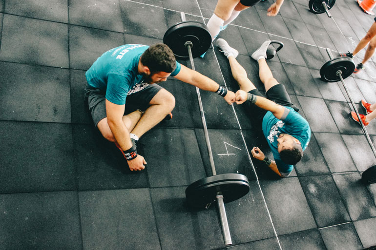 two man with barbell lying on mat