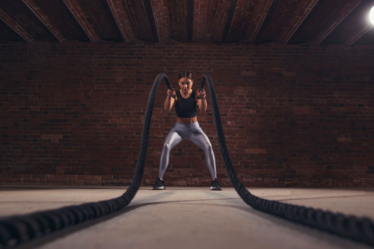 woman is holding black battle ropes