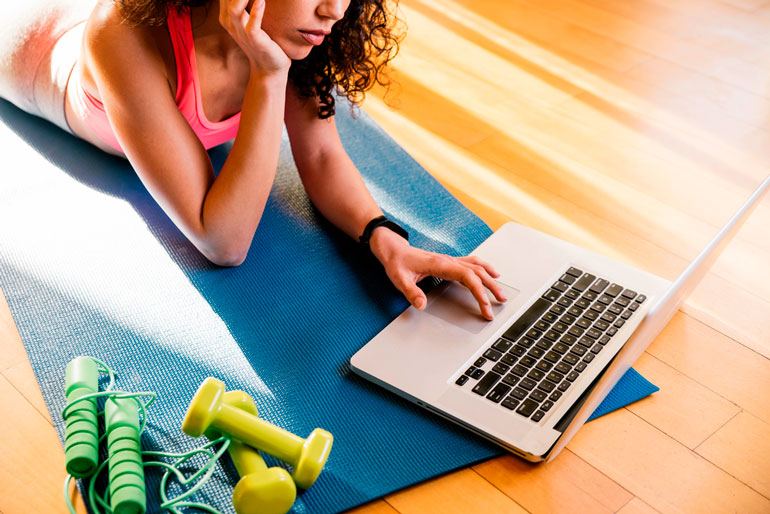 woman is looking at laptop on yoga mat