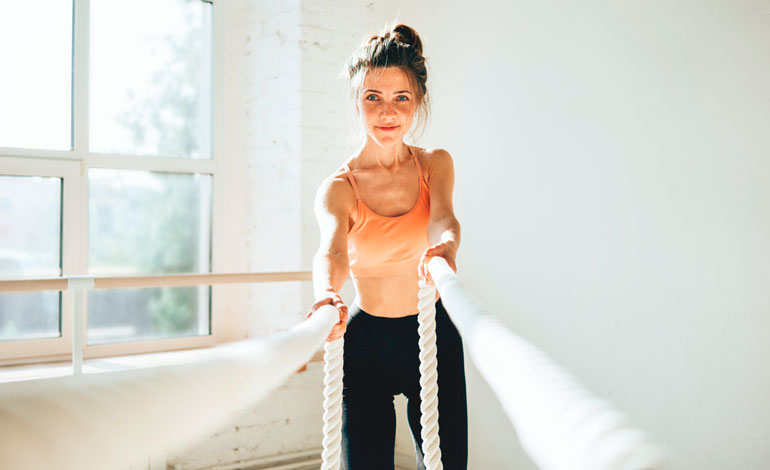 woman is working out with battle ropes