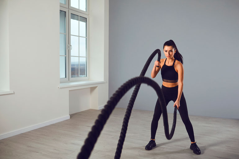 woman is working with battle ropes at home
