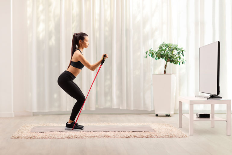 woman with exercise band in front of TV